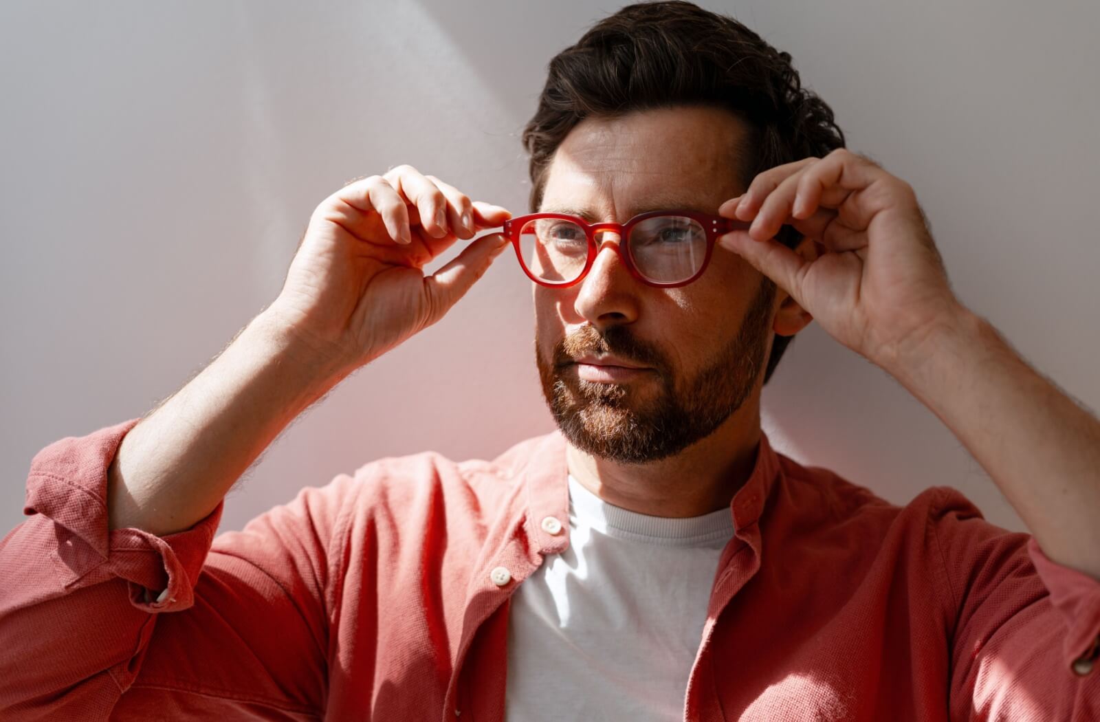 A person smiling while trying on a pair of glasses in an optical shop.